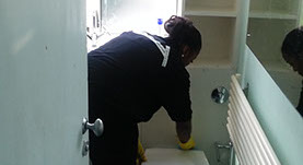 A female member of Gladiator Removal cleanteam is cleaning a bathroom wearing yellow washing up gloves.